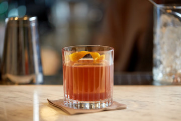 glass of cocktail with orange peel at bar