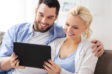 smiling happy couple with tablet pc at home