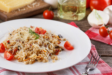 Porridge with vegetables in Italian. Risotto with vegetables. Still life with a dish and fresh vegetables on a wooden background. Rustic