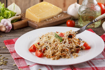Porridge with vegetables in Italian. Risotto with vegetables. Still life with a dish and fresh vegetables on a wooden background. Rustic
