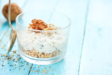 Healthy dietary breakfast - chia pudding with muesli, cereal flakes, walnut and honey in a glass bowl
