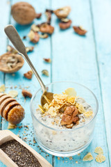 Healthy dietary breakfast - chia pudding with muesli, cereal flakes, walnut and honey in a glass bowl
