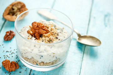Healthy dietary breakfast - chia pudding with muesli, cereal flakes, walnut and honey in a glass bowl