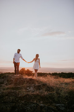 couple holding hands with sunset