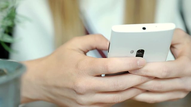 Girl texting messages with someone on white smartphone
