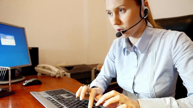 Businesswoman in headphones speaking and sitting on the workdesk