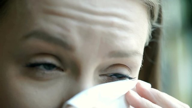 Girl looks downcast and wiping her tears with tissue while crying, steadycam shot
