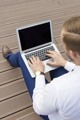 Handsome young businessman working on laptop sitting on the stairs outdoor