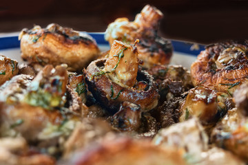 Whole mushrooms roasted on a grill with spices of golden color.