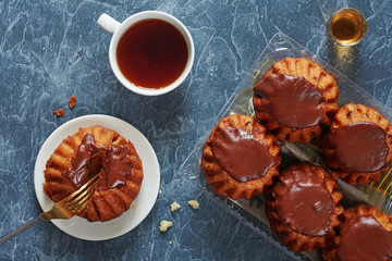 Top view of chocolate rum baba cake and cup of tea on gray concrete background. 