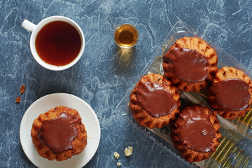 Chocolate rum baba cake and cup of tea on gray concrete background. Top view. 