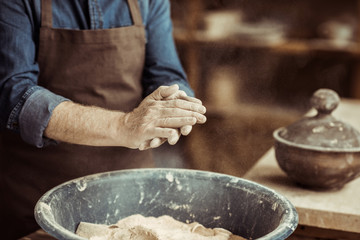 Close up of male potter hands taking clay from a bowl