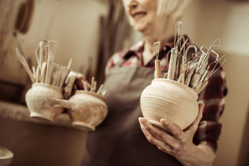 Senior woman holding bowls with pottery tools at at workshop - Powered by Adobe