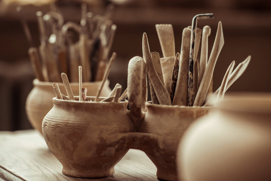 Close up of paint brushes with pottery tools in bowls on table