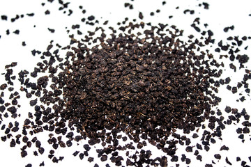 Black granulated dry tea on white