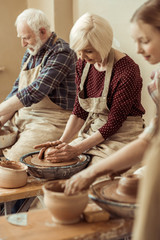Grandmother and grandfather with granddaughter making pottery at workshop