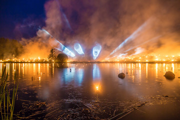 Naklejka na ściany i meble Light tubes on a horizon with a forest fire over a lake