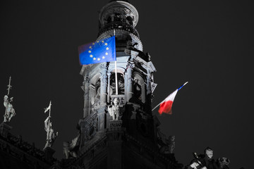 French flag waving over city hall in Paris, France. Flag of European Union on the Hotel de Ville. Selective focus. Elections in France.