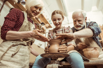 Grandmother and grandfather with granddaughter making pottery at workshop