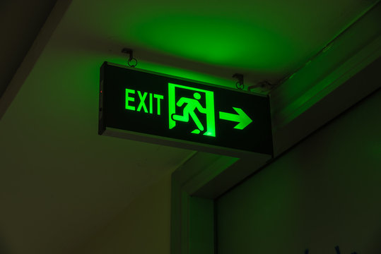 Close-up Exit neon or led sign in corridor point way out of resident apartment building in Hanoi, Vietnam. Lighted wall mounted green shining signboard show escape of emergency, urgency, firer concept