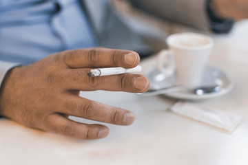 Cigarette in Male Hand With a Cup of Coffee. Smoking Addiction Concept.