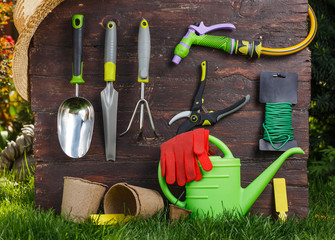 Gardening tools and a straw hat on the grass in the garden.