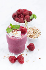 Fresh raspberry smoothie with nuts on a white background, vertical