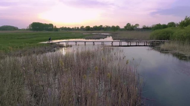 biking. man Rides on a wooden bridge across the river