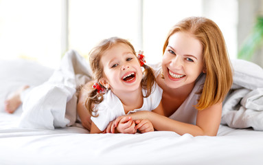 Happy family mother and child daughter laugh in bed