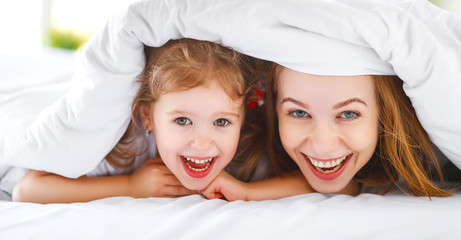 Obraz na płótnie Canvas Happy family mother and child daughter laugh in bed