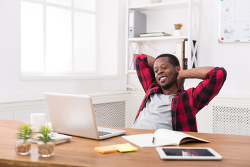 Young relaxed businessman with laptop in modern white office