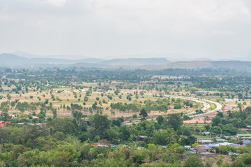 Fototapeta na wymiar Curve road, Village and town surrounded by countryside with mountain background in central of Thailand.