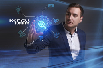Business, Technology, Internet and network concept. Young businessman working on a virtual screen of the future and sees the inscription: Boost your business