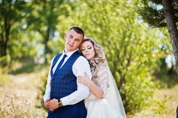 Fototapeta premium Happy wedding couple in love on sunny day stay near trees.