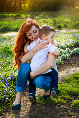 Fototapeta premium Young mother hugs her little son in the garden. Mother's Day concept