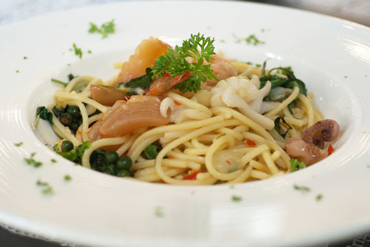 Spaghetti pasta sea food ingredient selective focus on white plate dish