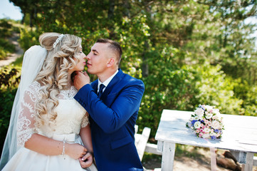 Happy wedding couple in love on sunny day sitting at wooden table at forest.