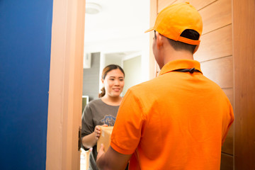 Asian woman accepting a delivery of boxes from deliveryman