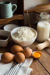 Baking ingredients flour, eggs, open yolk, milk, rolling pin, cupboard, raisins, rustic kitchen interior, utensils, dishware