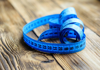 Blue measuring tape on wooden background
