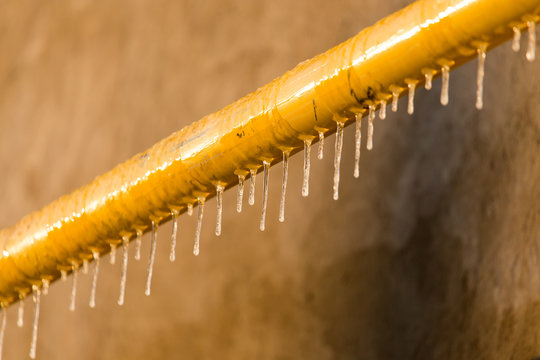 Icicles On A Yellow Pipe At Sunset