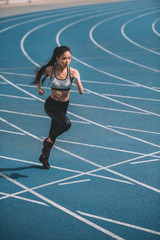 Fototapeta premium Athletic young sportswoman sprinting on running track stadium