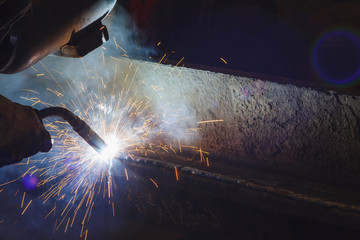 Worker welding steel by MIG/MAG weld (Argon welding) in industrial factory . - obrazy, fototapety, plakaty