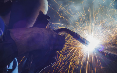 Worker welding steel by MIG/MAG weld (Argon welding) in industrial factory. - obrazy, fototapety, plakaty