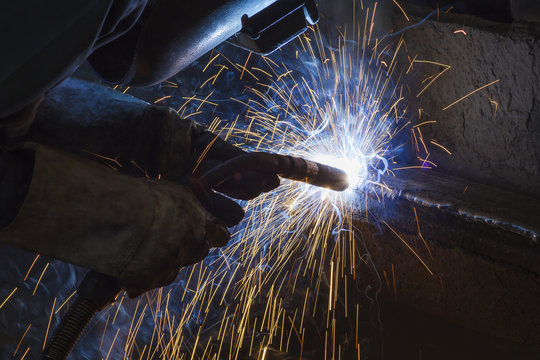 Worker welding steel by MIG/MAG weld (Argon welding) in industrial factory.
