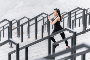 Sporty young woman in sportswear jogging on stadium stairs