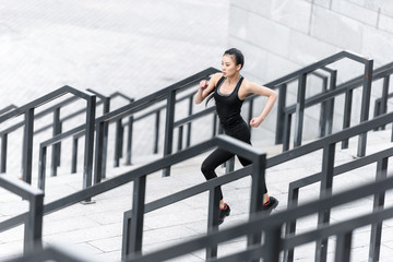 High angle view of athletic young woman in sportswear running on stadium stairs