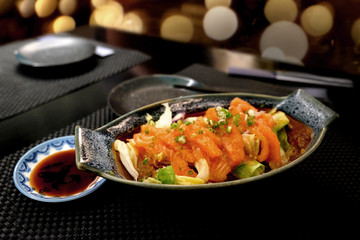 Top view of salmon sashimi serve on flower shape in white ice bowl boat with shoyu sauce on wood table background, Japanese style