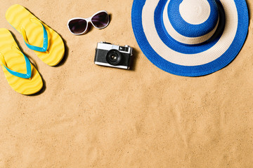 Pair of flip flop sandals, sunglasses, hat and camera.