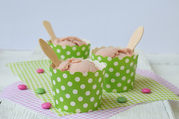 Pink milk ice cream in a paper cup on a white wooden background. Berry sorbet. Place for text